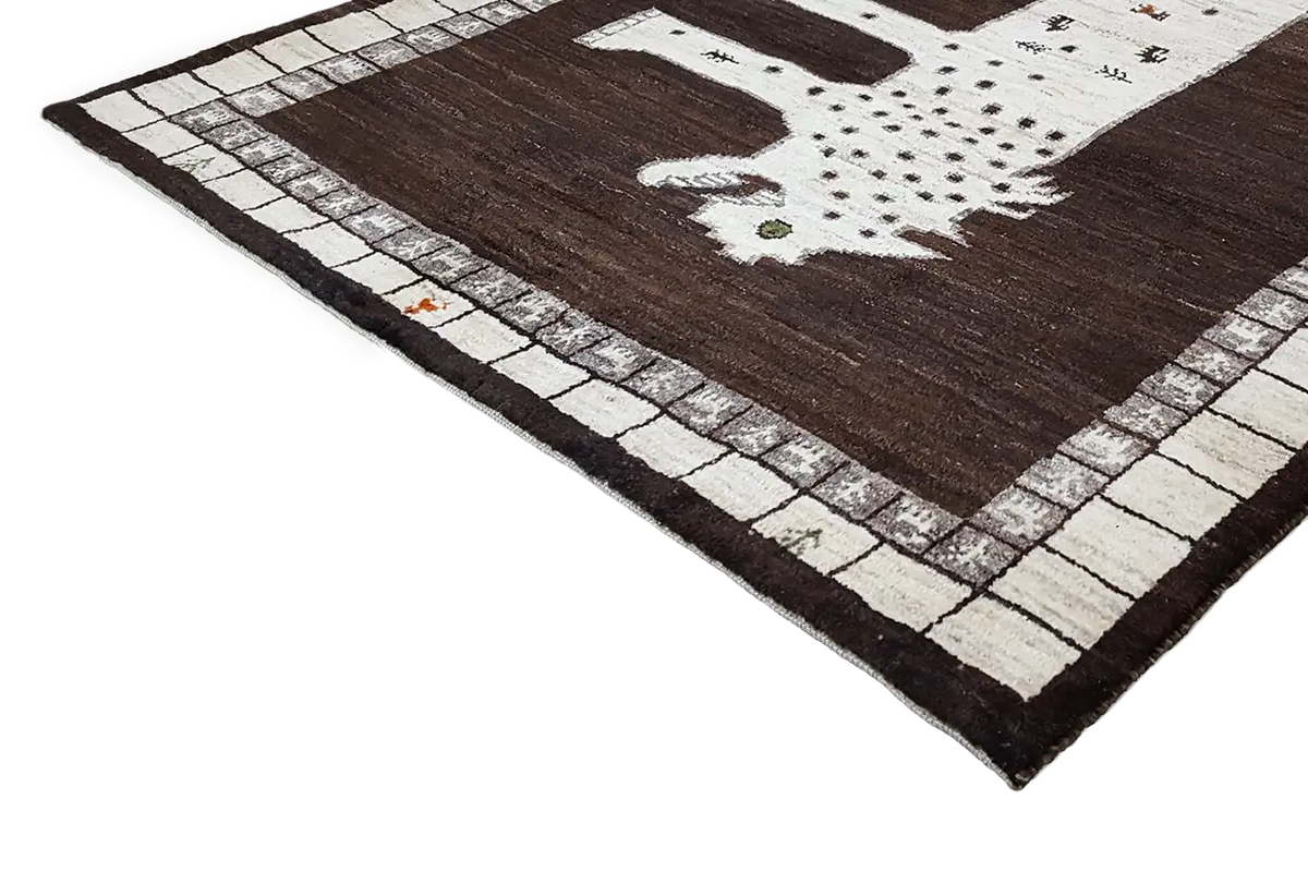 Gabbeh rug viewed from the side, with a lion motif and decorative border visible along the edge