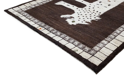 Gabbeh rug viewed from the side, with a lion motif and decorative border visible along the edge